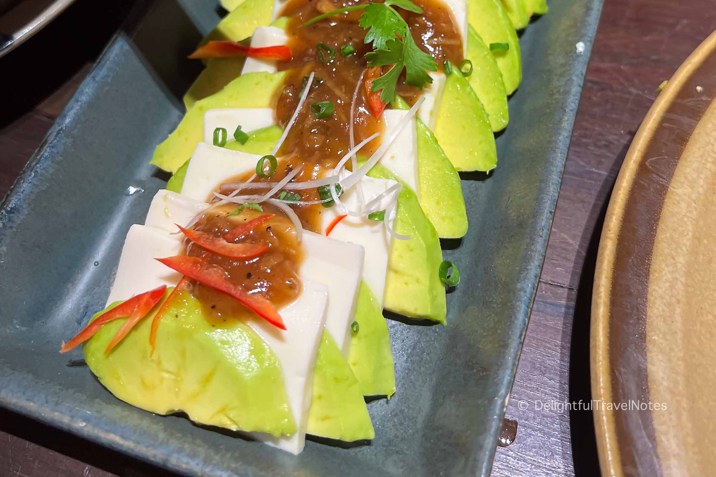 a plate of avocado and silken tofu with lemongrass ginger sauce at Pi vegetarian restaurant in Saigon