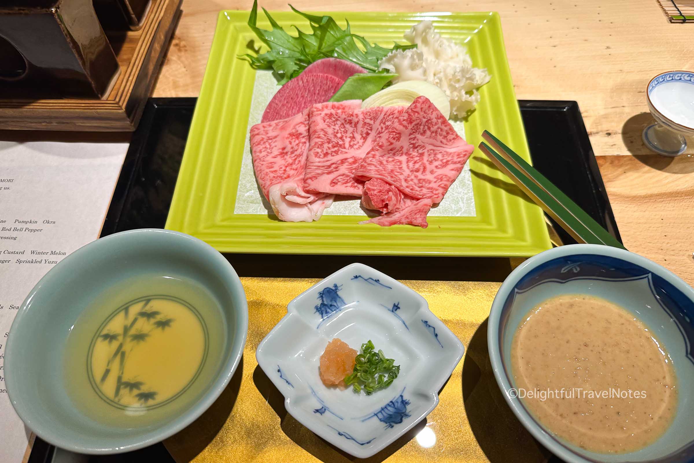 a plate of Hida beef and bowls with dipping sauce for shabu shabu hotpot in Madoka no Mori kaiseki dinner