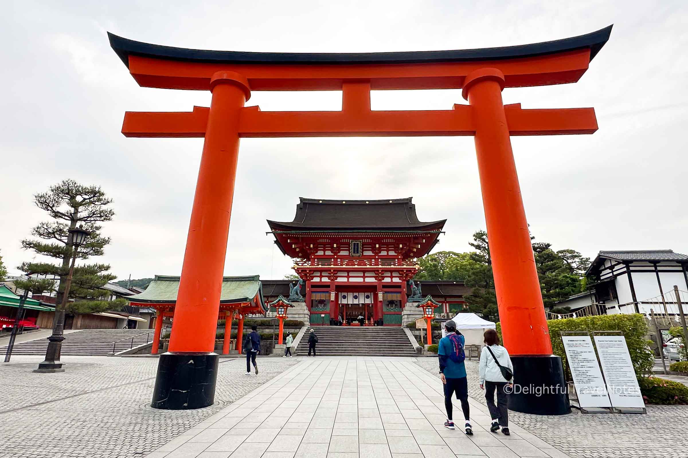 two people walking along the side under torii gate - a shrine etiquette practice in Japan