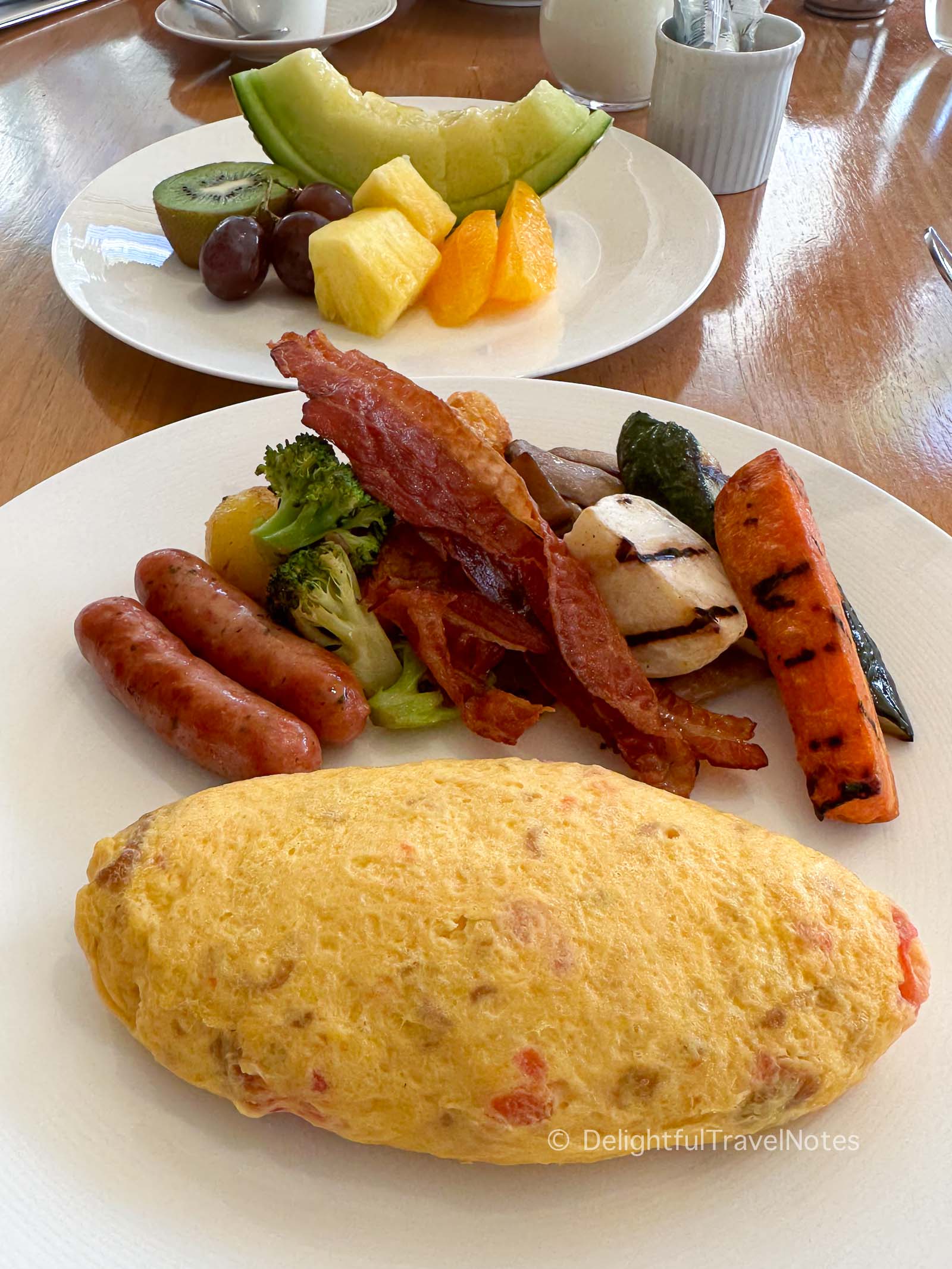 a plate of omelet with bacon, sausage and fruit platter for breakfast at Hyatt Regency hotel in Hakone