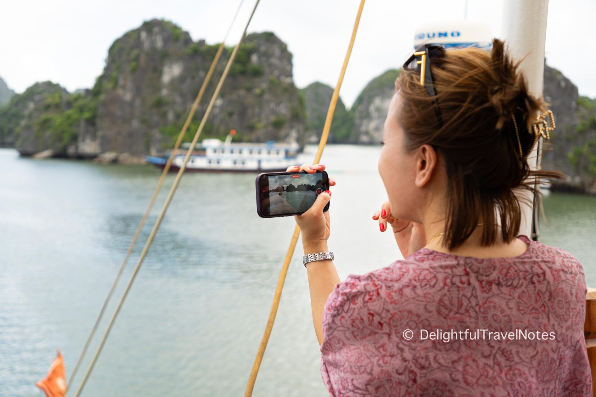 a woman capturing the scenery in Lan Ha Bay with a smartphone.