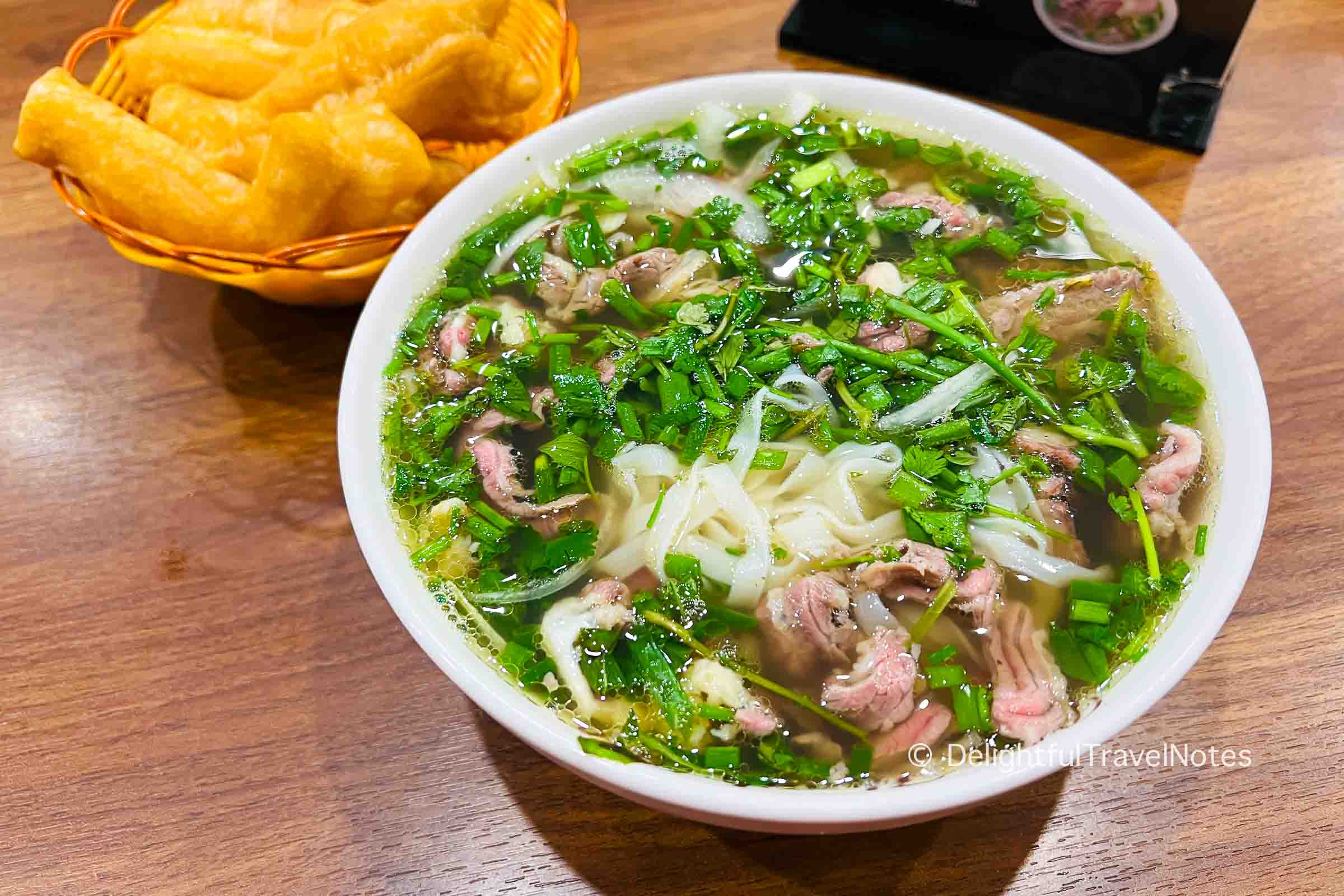 a bowl of beef pho noodle soup with well-done beef and rare beef at Pho Thanh Beo noodle shop in Hanoi.