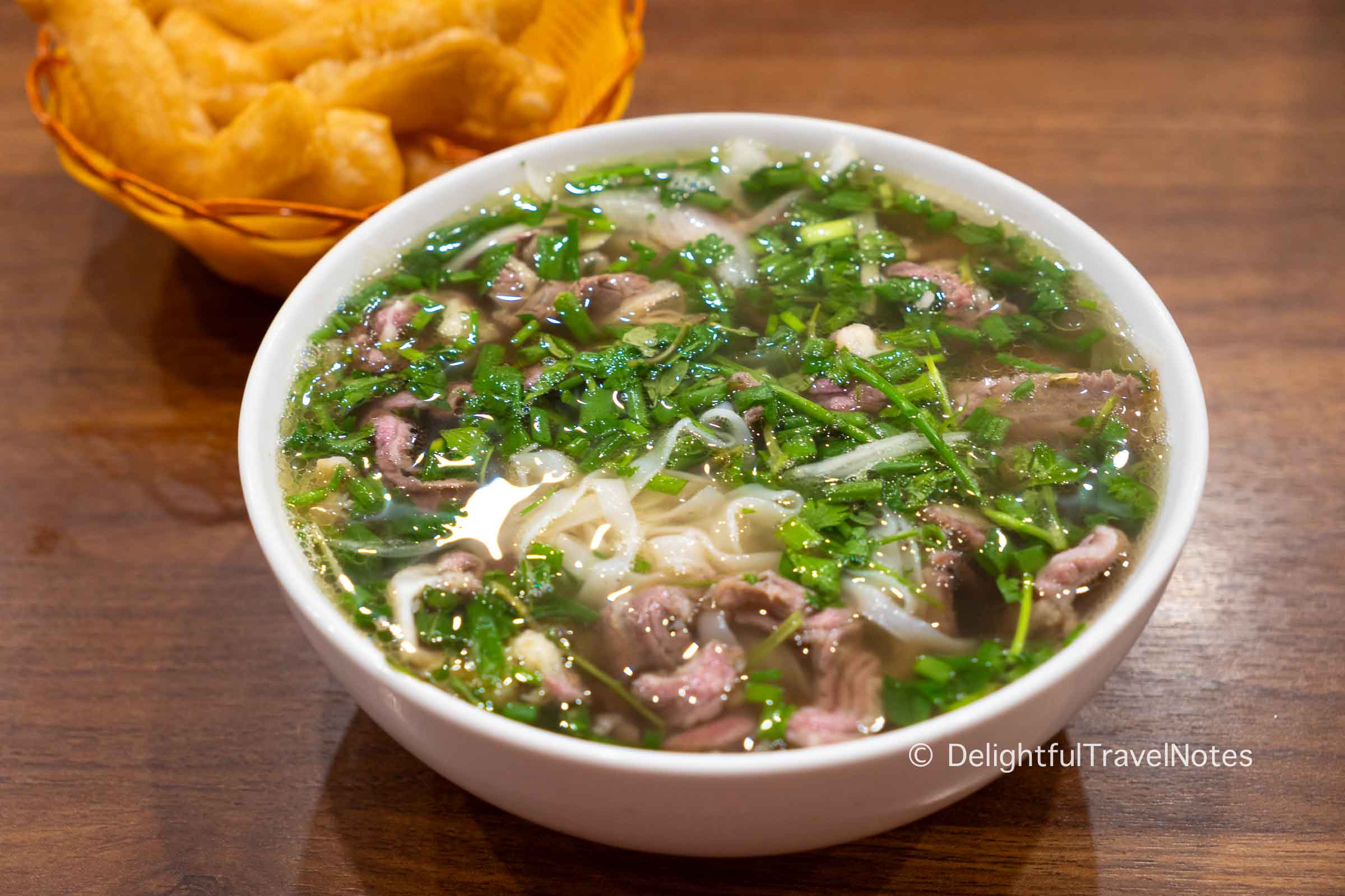 a bowl of beef pho noodle soup with cooked beef and rare beef at Thanh Beo noodle shop in Hanoi.