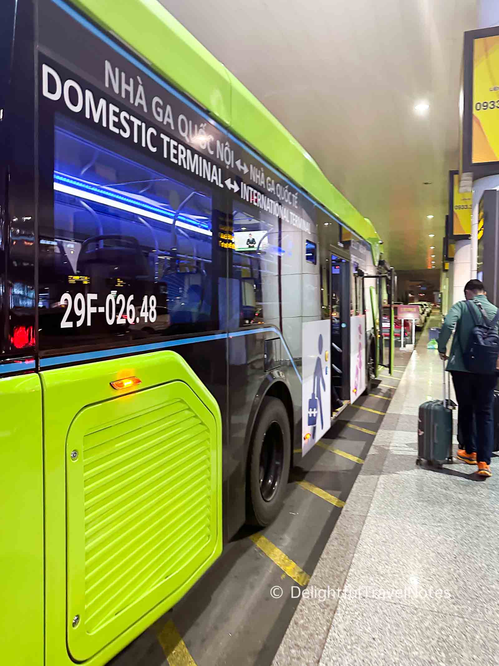 a green shuttle bus to transfer between terminals at Noi Bai Airport in Hanoi.