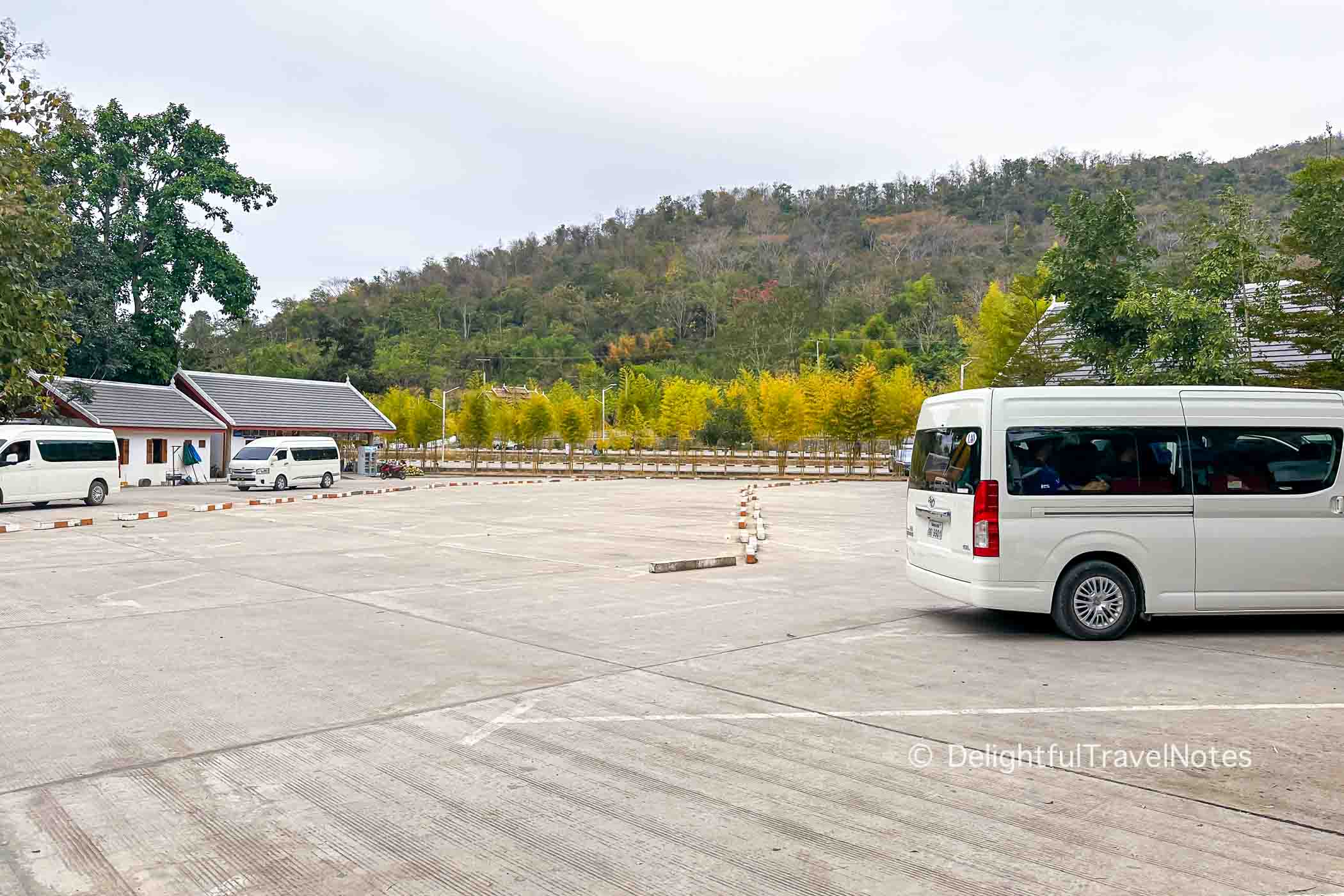 Kuang Si Falls parking lot with few vehicles in the morning.