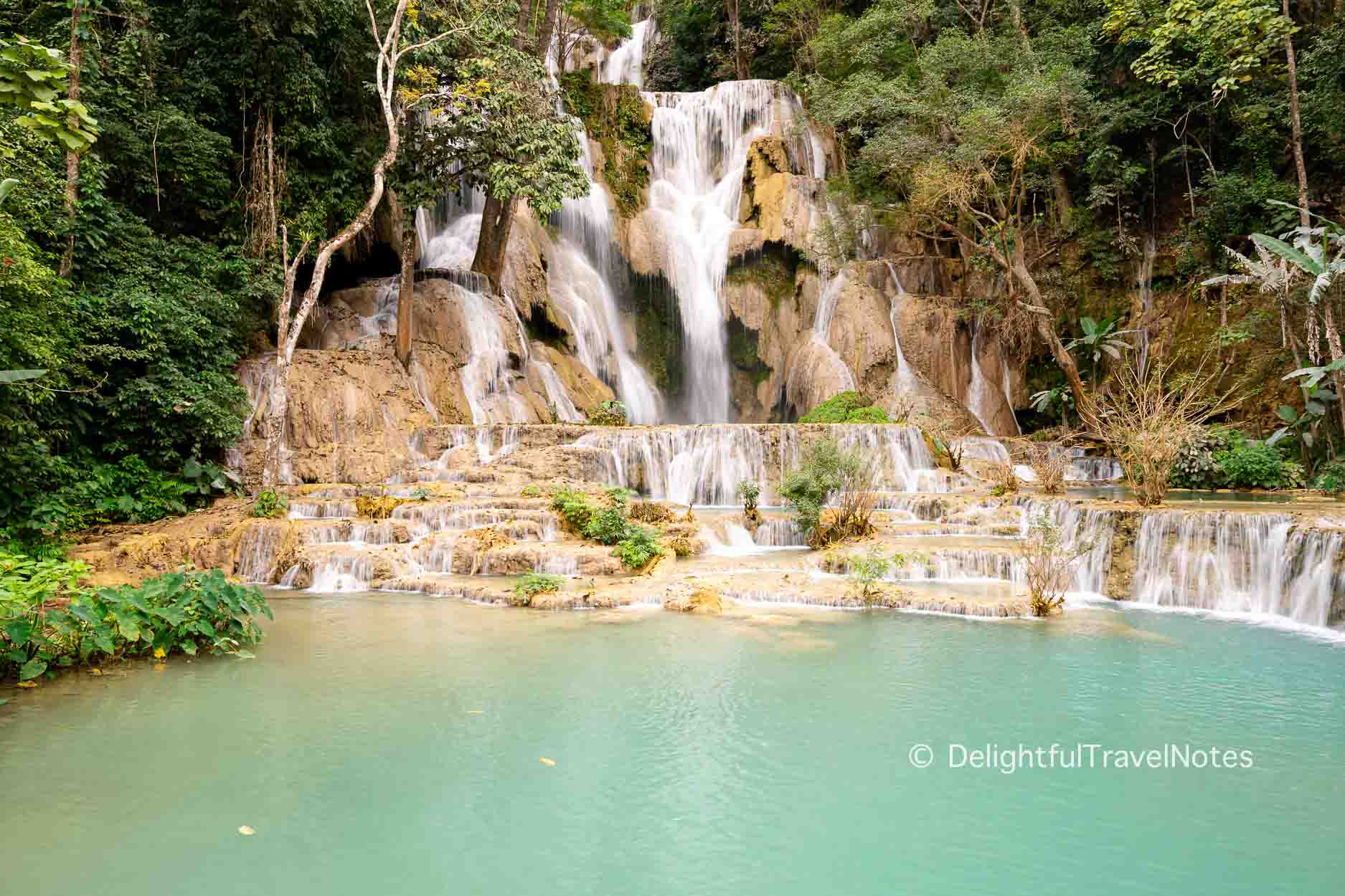 the main Kuang Si waterfall with its cascading water and milky blue pool.