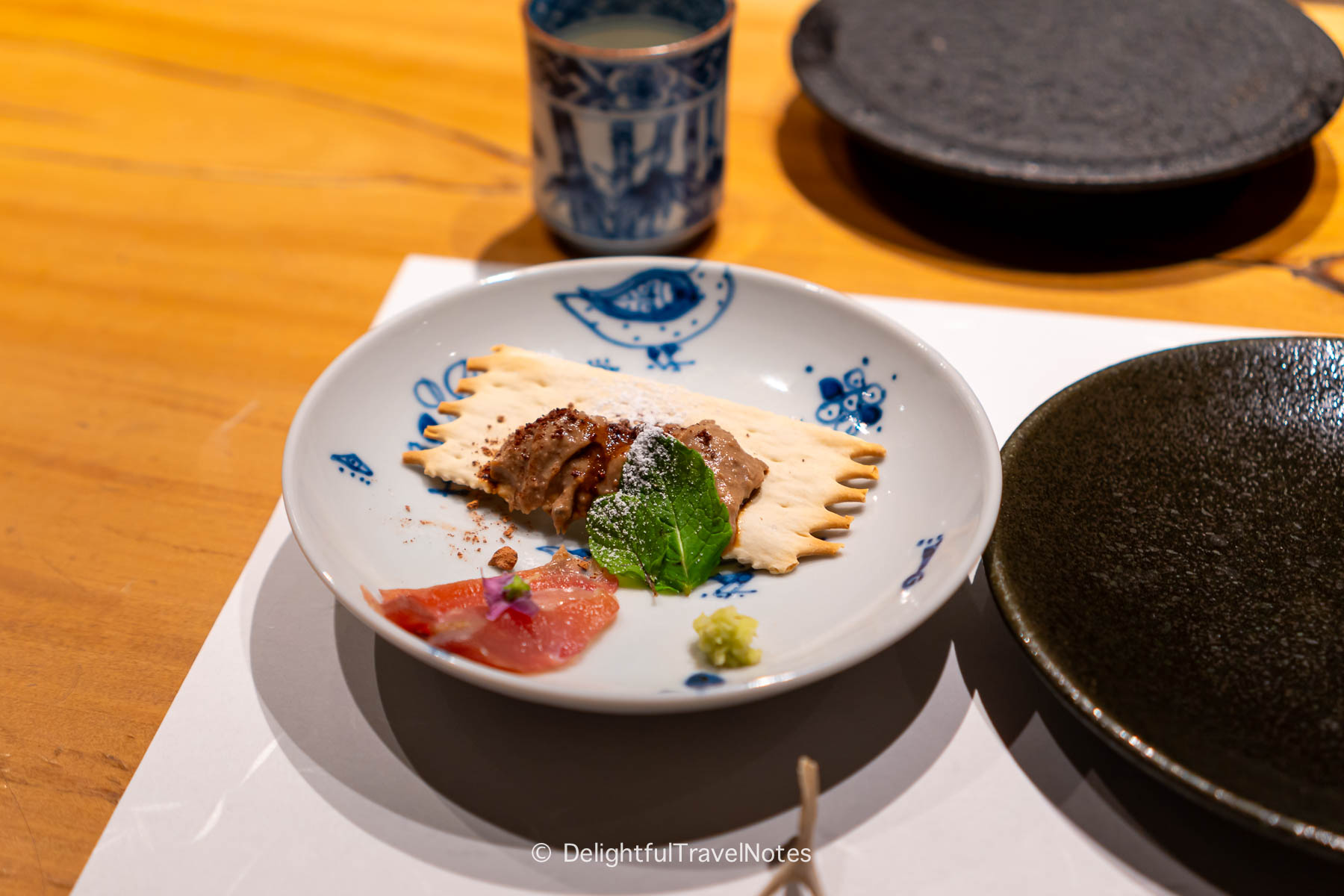 a small plate of crackers with chicken liver pate at Yakitori Taimatsu in Osaka.