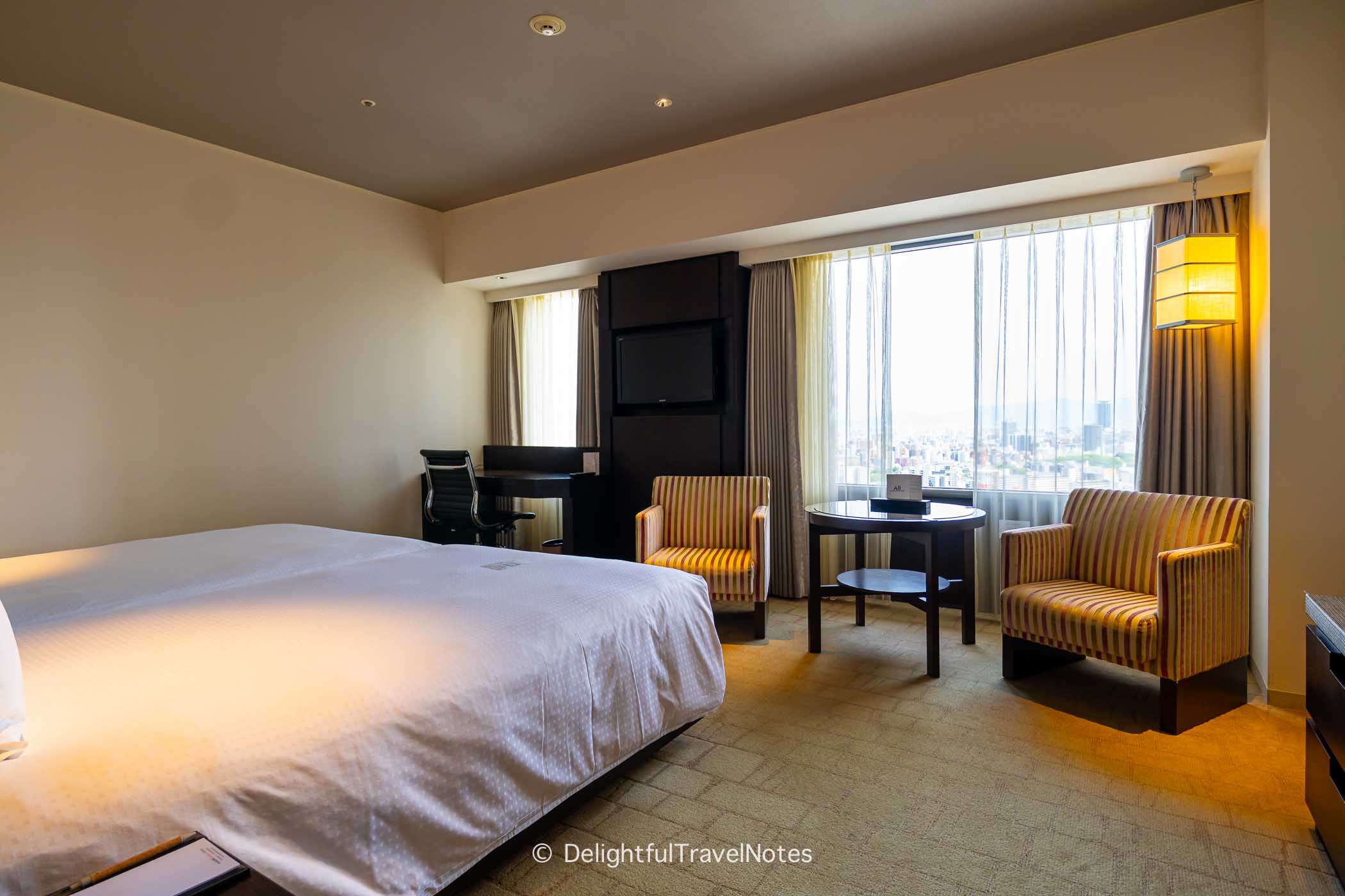 room at the Swissotel Nankai with twin beds, couches, table, desk and chair.