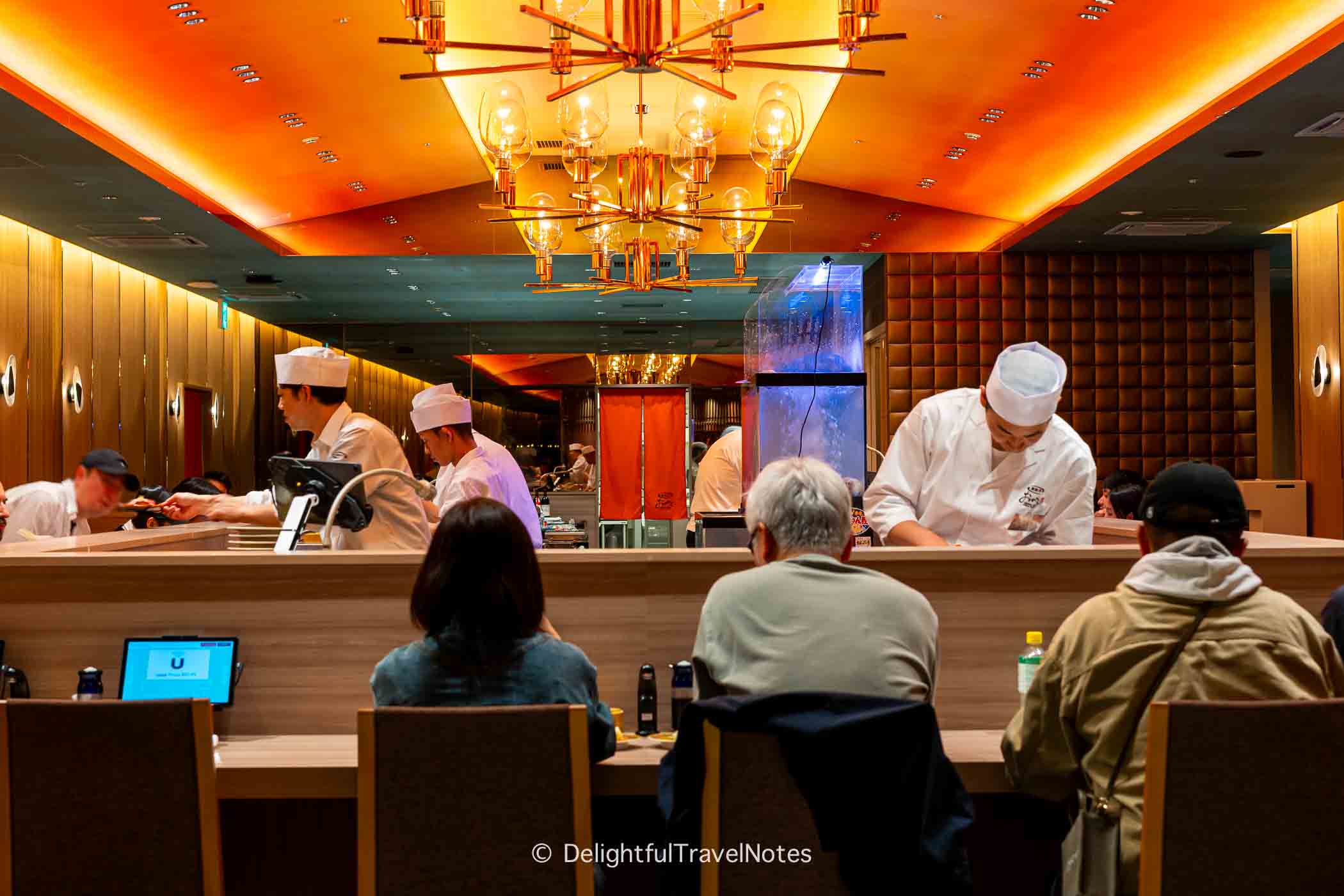 inside Kaiten Sushi Ginza Onodera in Osaka with counters and chefs working.