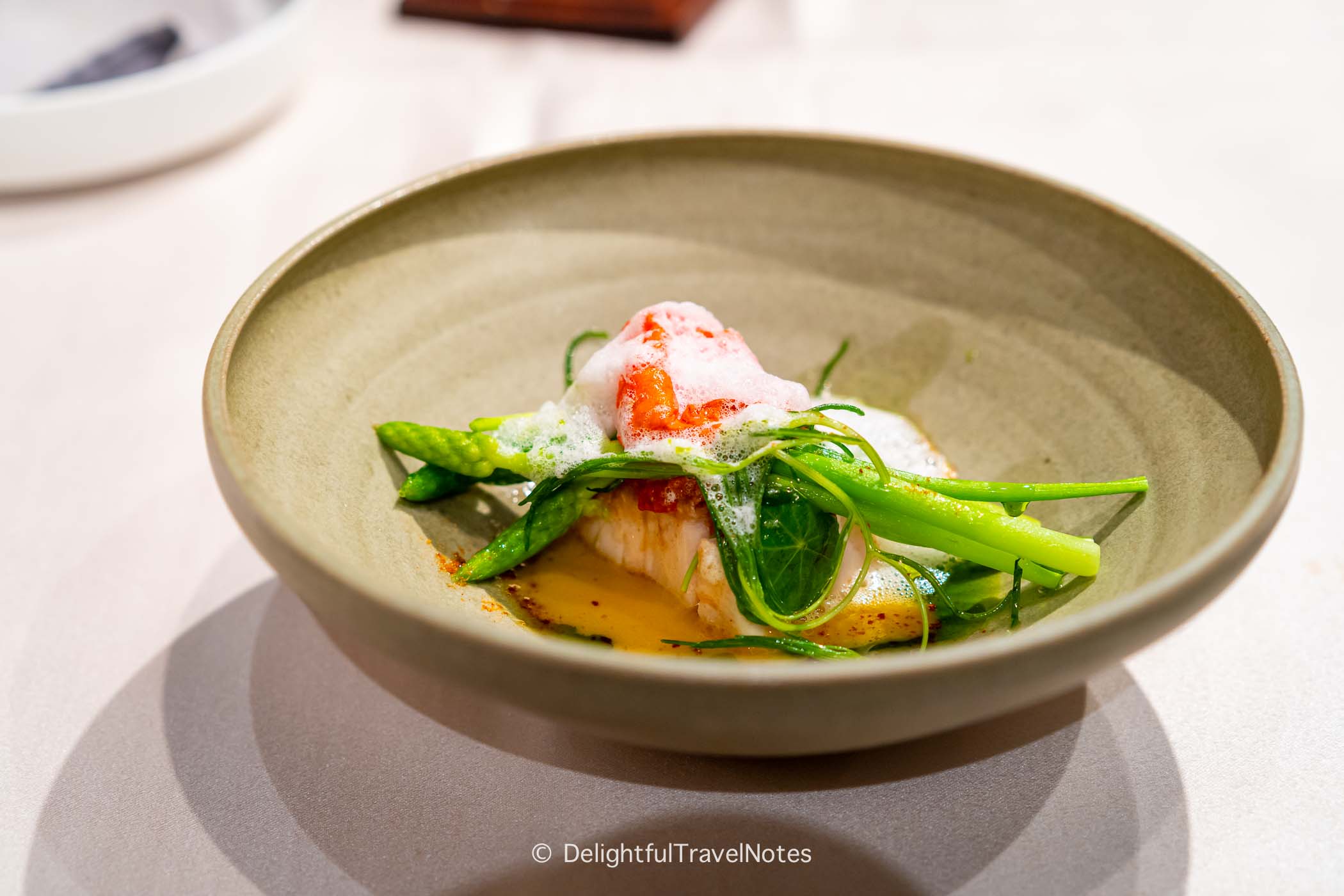 a plate of kinmedai with saffron sauce and thyme oil.