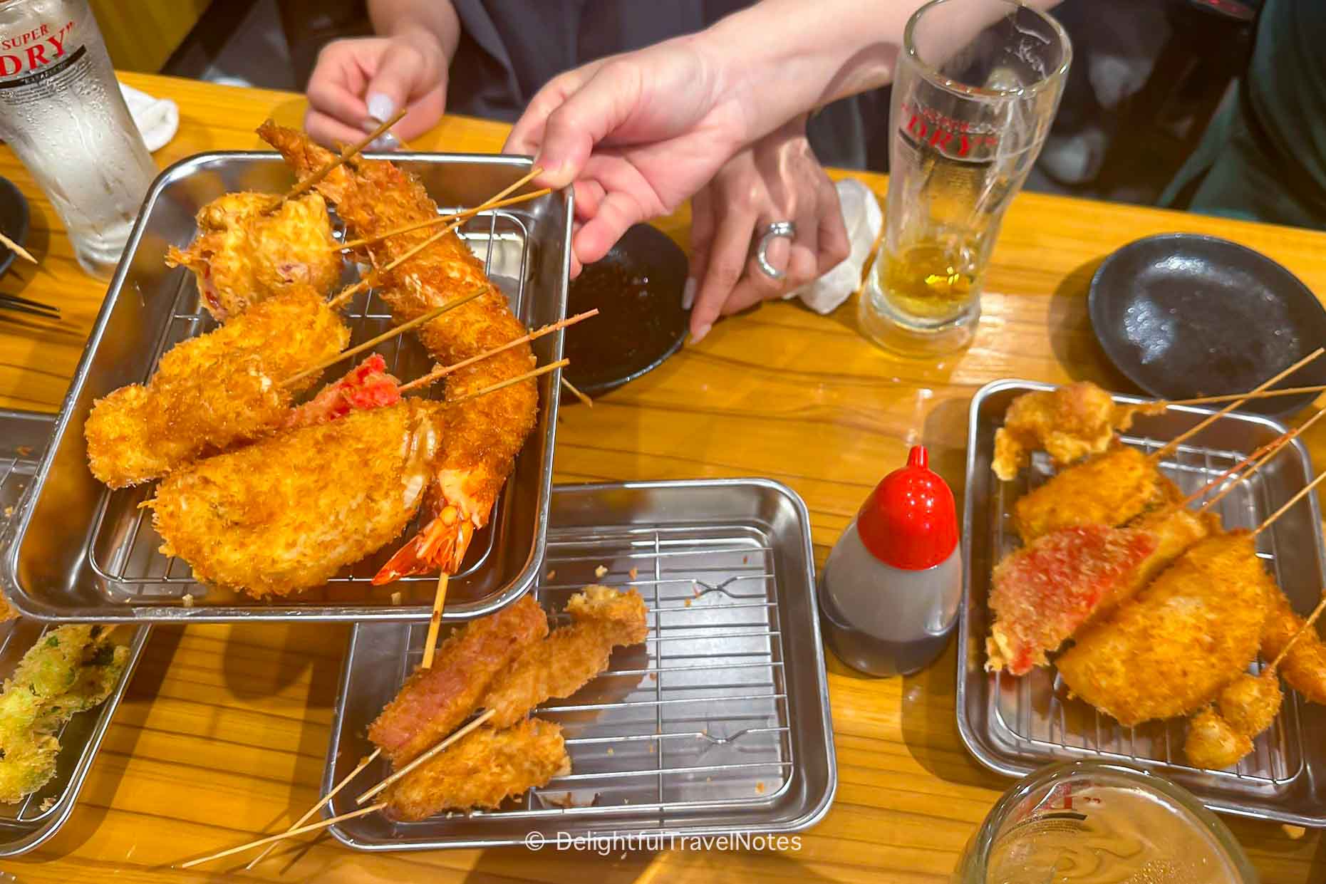 a table with trays of kushikatsu/kushiage, a must-try food in Osaka.
