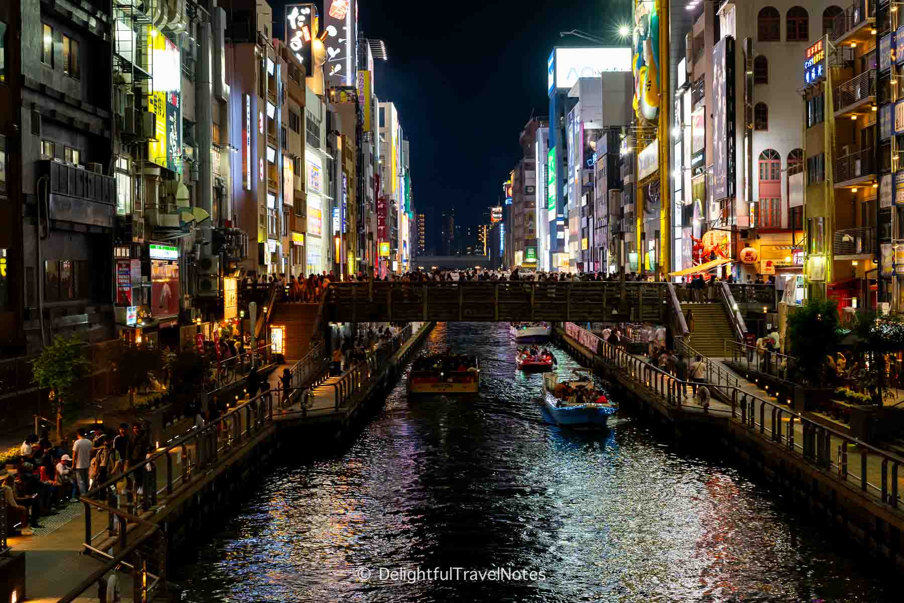 Dotonbori canal at night full of tourists in Osaka.