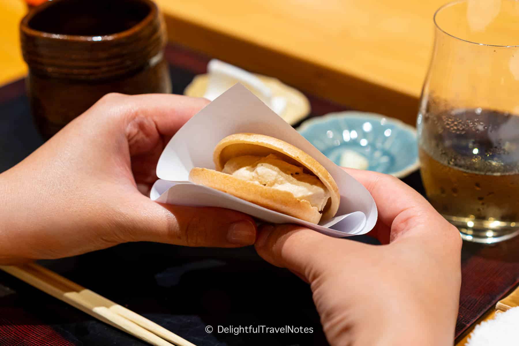 guest holding monaka ice cream sandwich served at Sushi Issei in Kanazawa.