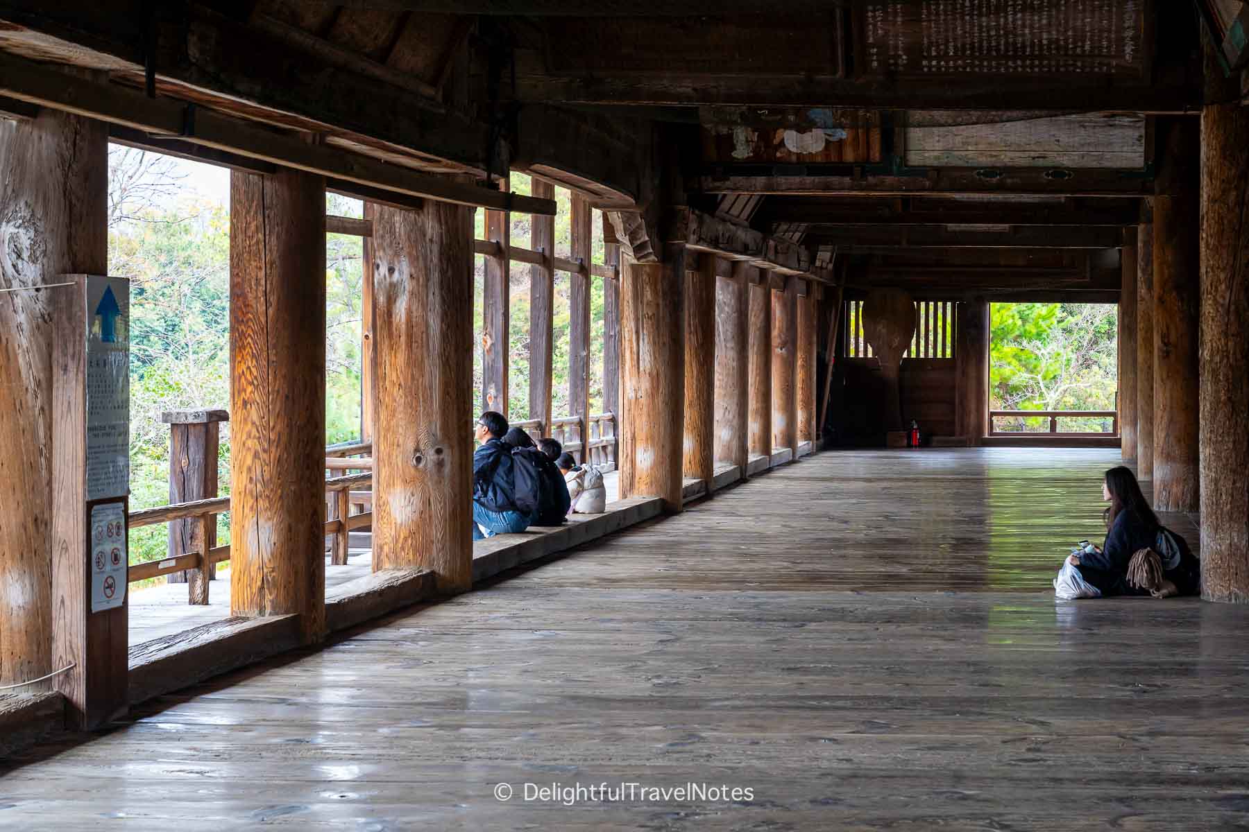 Quiet atmosphere with few visitors relaxing inside Hokoku-jinja on Miyajima Island.